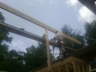 Carpenter setting a ridge beam over a new addition frame — Ice Dam Removal by Roofing Brothers in Godley