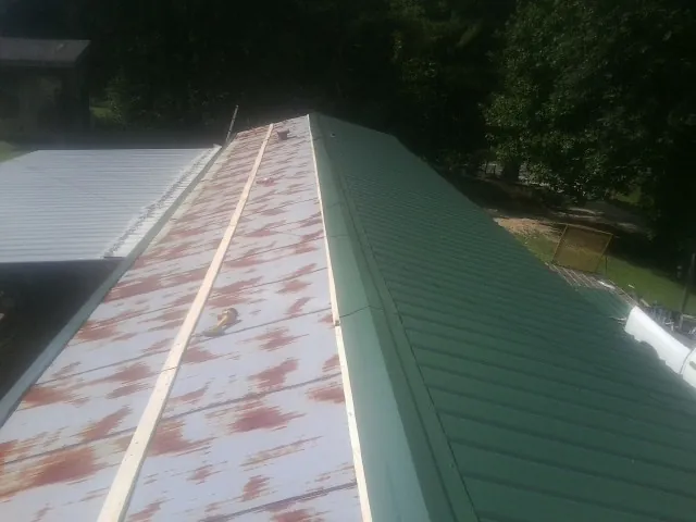 Old rusted panels beside newly installed green metal roofing — Wind Damage Roof Repair by Roofing Brothers in Godley