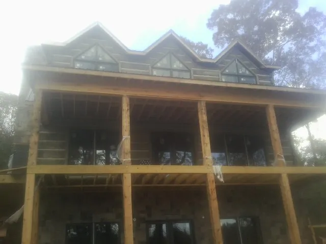 Dormers and porch framing on a large log home under construction — Roof Coating work by our crew in Godley