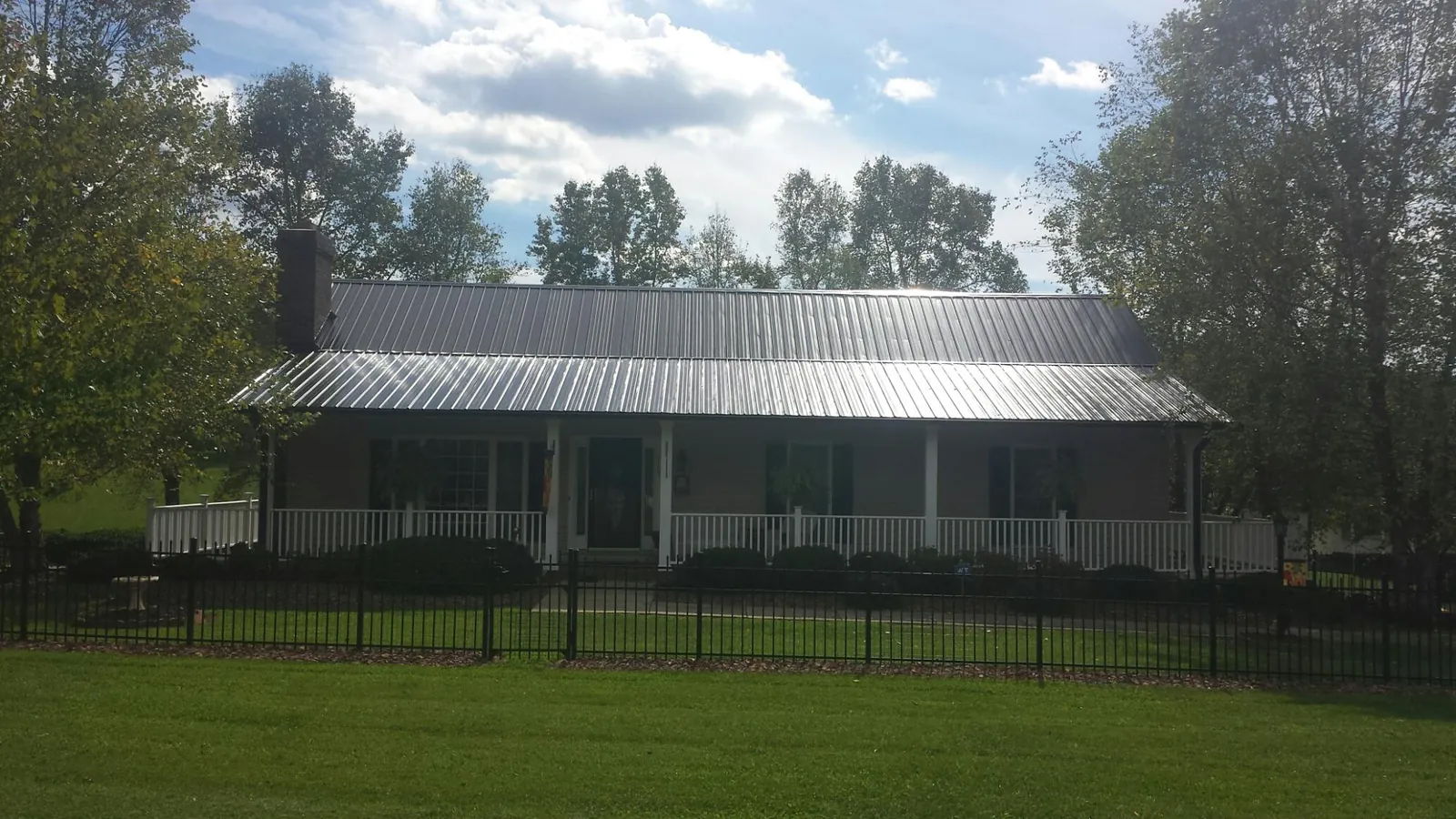 Gray metal roof on a brick ranch with a full width front porch — Gutter Guard Installation work by our crew in Godley