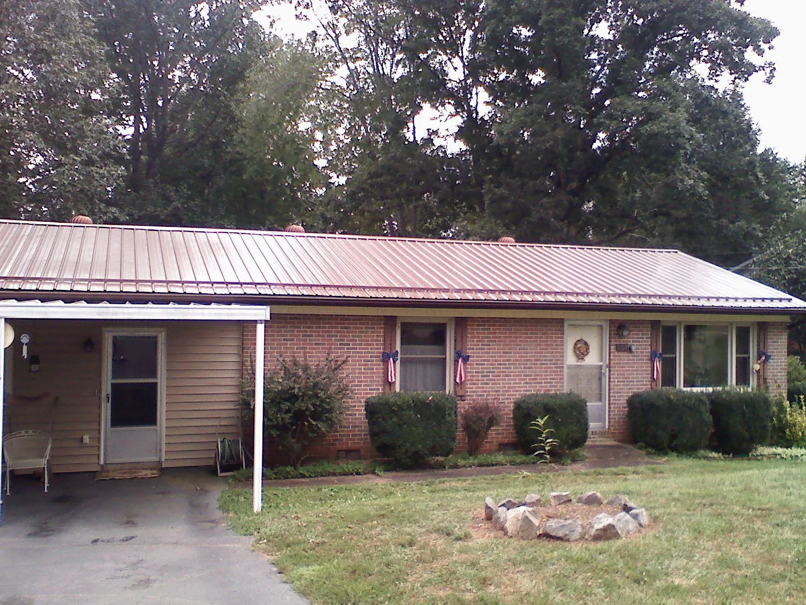 Bronze metal roof and carport on a brick ranch home — Roof Repair work by our crew in Godley